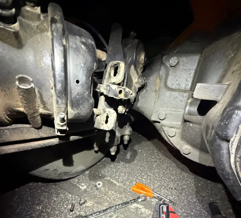 Driveline and axle repair underneath an 18-wheeler with tools on the ground