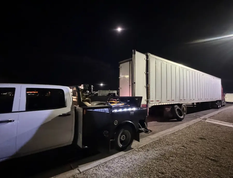 White mobile service truck parked next to a dry van trailer at night