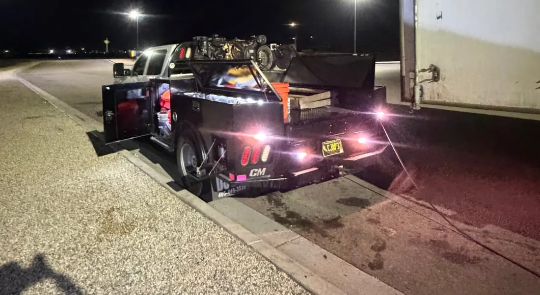 BULLZ service truck with tool boxes open beside a semi trailer at night under parking-lot lights